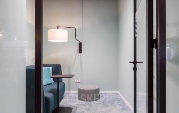 Moderne, rustige kantoorruimte te huur met zachte blauwe tinten, comfortabele bank en bijzettafel in Stadhuisplein 10, Eindhoven. Ideaal voor informele vergaderingen of rustige werkzaamheden.