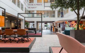 Moderne, lichte kantoorruimte huren in Eindhoven Centrum op Stadhuisplein 10, met stijlvolle inrichting, open werkplekken, kleurrijk interieur en innovatieve design elementen.