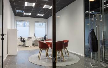 Moderne kantoorruimte met glazen deuren, vergadertafel en bureaus gelegen op Stadhuisplein 10, Eindhoven Centrum. Ideaal voor zakelijke huur met een stijlvolle, functionele inrichting.