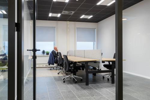 Binnenzicht van een kantoorpand op Stadhuisplein 10, Eindhoven Centrum, met werkplekken en een persoon in zakelijk overleg. Ideale locatie voor kantoorruimte huren.