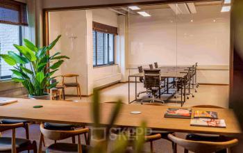 Kantoorruimte huren op Emmasingel 33 in Eindhoven Centrum met een vergaderruimte, houten tafel en comfortabele stoelen. Planten voegen een natuurlijk element toe aan het interieur.