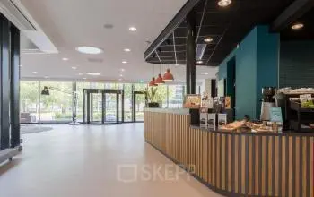 Moderne entree van het kantoorpand aan Professor Dr Dorgelolaan 14 in Eindhoven Centrum met een stijlvolle balie en glazen deuren. Het interieur oogt professioneel voor wie kantoorruimte huren overweegt.