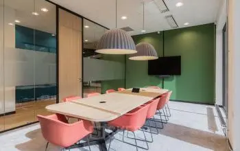 Vergaderruimte in kantoorpand met moderne verlichting, houten tafel en rode stoelen, gelegen op Professor Dr Dorgelolaan 14, Eindhoven Centrum. Ideale plek voor kantoorruimte huren.