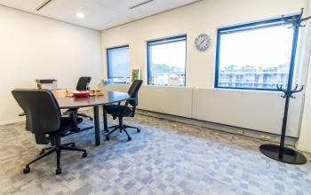 Vergaderruimte in kantoorpand aan Paradijslaan 30-38, Eindhoven Centrum met vier stoelen rond een tafel, uitzicht naar buiten.