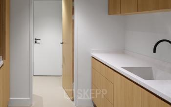 Moderne pantry in kantoorpand op Paradijslaan 30-38, Eindhoven Centrum. Houten kasten en een wit werkblad creëren een lichte sfeer voor kantoorruimte huren.