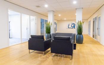 Modern kantoorpand te huur op Paradijslaan 30-38 in Eindhoven Centrum. De ruimte is ingericht met comfortabele zitplaatsen en planten, ideaal voor zakelijke activiteiten.
