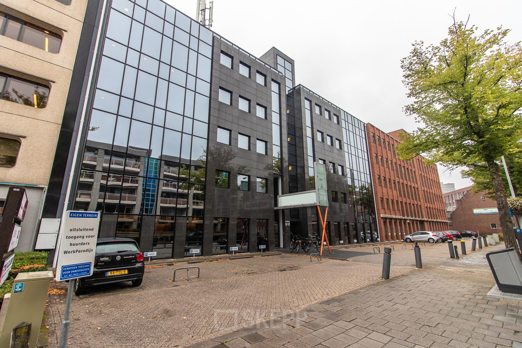 Extern zicht op kantoorpand Paradijslaan 30-38 in Eindhoven Centrum. Glas en steen gevel met parkeerplaatsen.