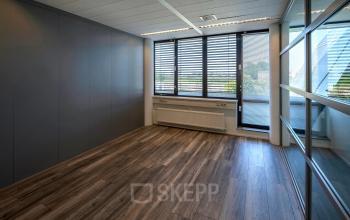 Leegstaand kantoor aan Noord Brabantlaan 303-307 in Eindhoven De Hurk, met houten vloer en grote ramen voor veel lichtinval, ideaal voor kantoorruimte huren.