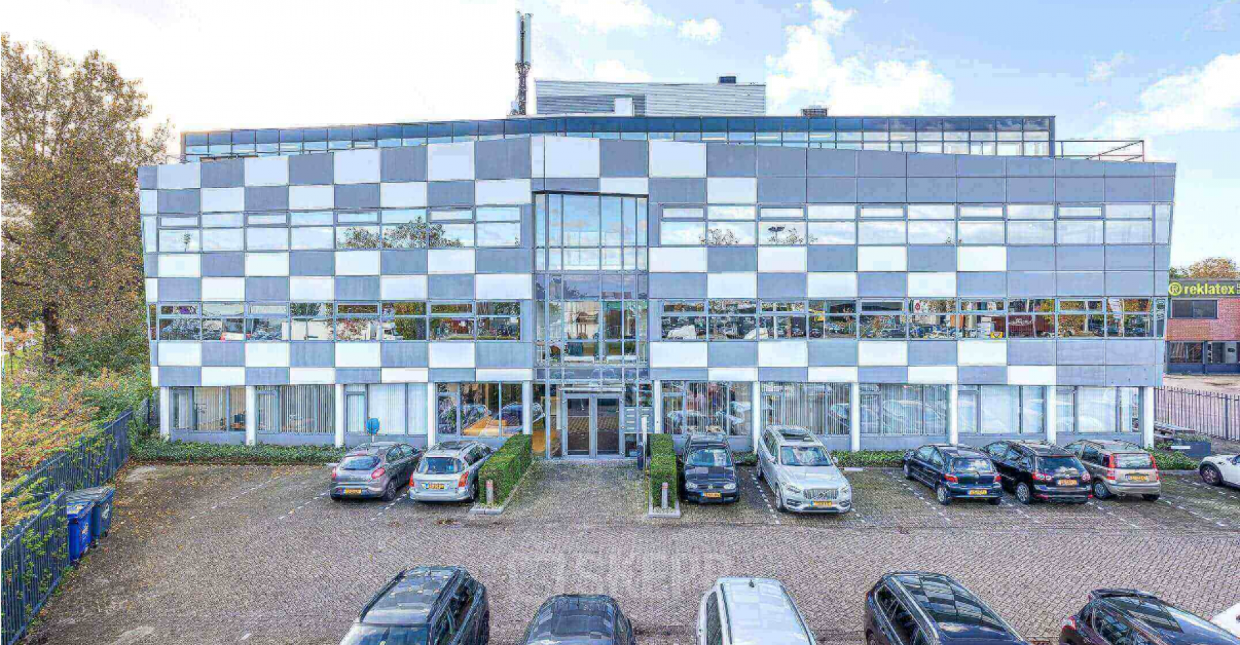 Voorzijde van het kantoorpand op Meerenakkerplein 1-10 in Eindhoven De Hurk met parkeerplaatsen voor het gebouw.