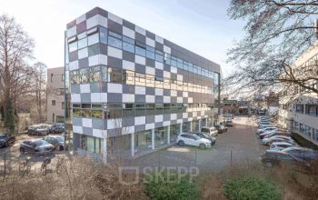Een modern kantoorpand op Meerenakkerplein 11-20 in Eindhoven De Hurk, met gekleurde panelen en parkeerplaatsen aan de voorkant. Ideale locatie voor wie kantoorruimte wil huren.