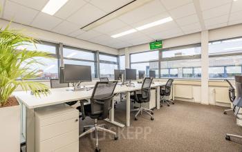 Kantoorruimte huren in Eindhoven De Hurk: moderne werkplek met bureaus, stoelen en computers, geschikt voor productief werken. Grote ramen bieden veel natuurlijk licht.
