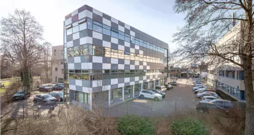 Een modern kantoorpand op Meerenakkerplein 11-20 in Eindhoven De Hurk, met gekleurde panelen en parkeerplaatsen aan de voorkant. Ideale locatie voor wie kantoorruimte wil huren.