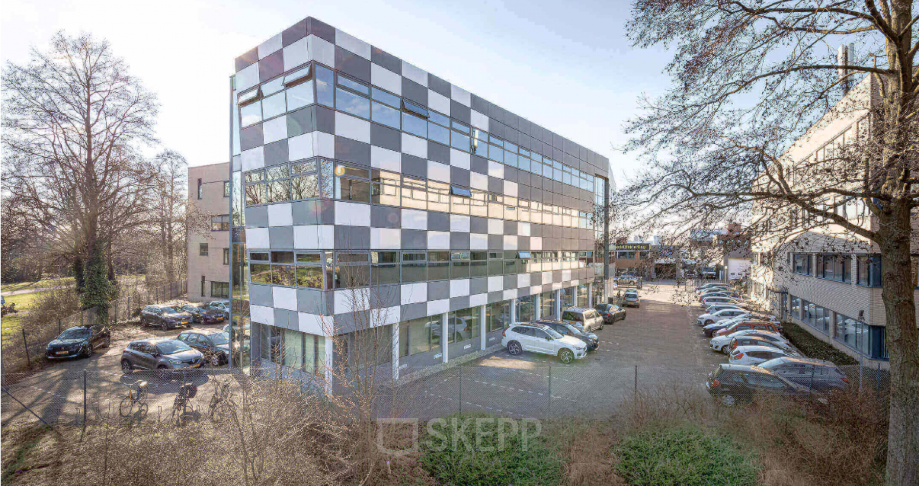 Een modern kantoorpand op Meerenakkerplein 11-20 in Eindhoven De Hurk, met gekleurde panelen en parkeerplaatsen aan de voorkant. Ideale locatie voor wie kantoorruimte wil huren.