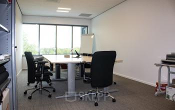 Kantoorruimte huren op Hurksestraat 60, Eindhoven De Hurk. Kantoorpand met lichte werkruimte, grote ramen, tafel, en stoelen. Gemeubileerd en klaar voor gebruik.