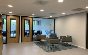 Kantoorruimte huren aan de Hurksestraat 60, Eindhoven de Hurk; moderne setting met comfortabele stoelen en vergaderruimte zichtbaar door glazen wanden.