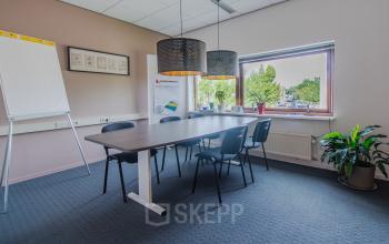Vergaderruimte in kantoorpand aan Le Havre 114-127, Eindhoven Noord, met grote tafel, stoelen, flip-over en raam met uitzicht.