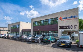 Kantoorpand met parkeerplaats aan de voorzijde op Le Havre 114-127, Eindhoven Noord. Verschillende auto's staan geparkeerd voor het gebouw, met zichtbare bedrijfsnamen op de gevel.