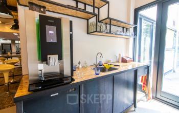Gezellige pantry met een moderne koffieautomaat en een werkblad bij kantoorruimte te huur op Weegschaalstraat 3, Eindhoven Noord.