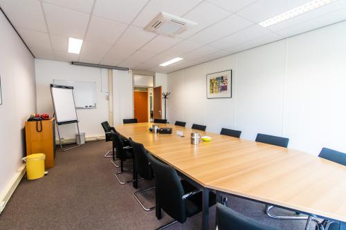 Vergaderruimte in kantoorpand op Weegschaalstraat 3, Eindhoven Noord, met lange tafel en comfortabele stoelen. De ruimte is ideaal voor vergaderingen en zakelijke bijeenkomsten.