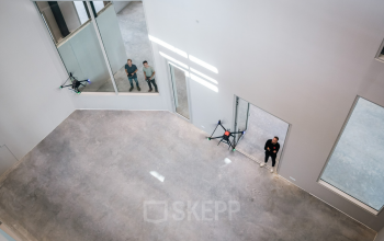 Kantoorruimte huren op Frederiklaan 10A, Eindhoven Strijp-S, met hoge plafonds en ruime, lichte indeling. Twee personen bestuderen de omgeving vanuit een inspirerend perspectief. Moderne locatie voor efficiënte zakelijke activiteiten.