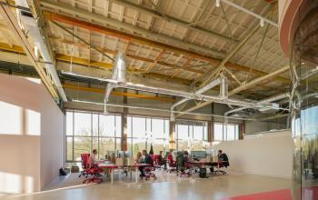 Kantoorruimte huren aan Frederiklaan 10A in Eindhoven Strijp-S, met moderne open vloerindeling, grote ramen en mensen die aan laptops werken.