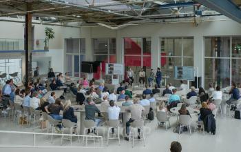 Een ruime, lichte vergaderzaal in een kantoorpand op Frederiklaan 10A, Eindhoven Strijp-S, gevuld met professionals die deelnemen aan een presentatie. Ideaal om kantoorruimte te huren voor zakelijke bijeenkomsten.