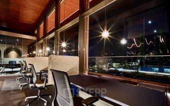 Moderne kantoorruimte met uitzicht op de nachtelijke skyline van Eindhoven, gedeeltelijk gemeubileerd met bureaus en stoelen. Perfect voor wie kantoorruimte wil huren. Gelegen op Achtseweg Zuid 159R, in Strijp-S.