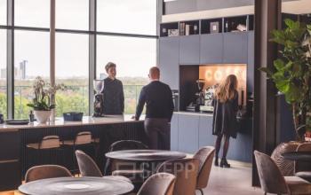 Gezellige kantineruimte in kantoorpand aan Achtseweg Zuid 159R, Eindhoven Strijp-S, met mensen die genieten van een koffiepraatje. Ideaal voor kantoorruimte huren met uitzicht en moderne voorzieningen.