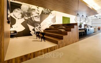 Modern ingerichte kantoorpand met houten trappen, kunst aan de muur en stijlvolle hanglampen op Frederiklaan 10E, Eindhoven Strijp-S. Ideaal voor bedrijfscultuur met ruimte voor creativiteit en bijeenkomst.