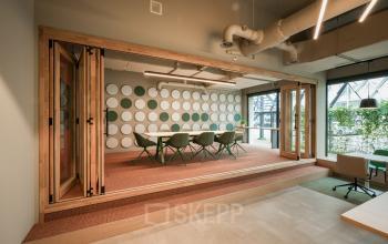 Moderne kantoorpand op Frederiklaan 10E, Eindhoven Strijp-S, met vergadertafel en zitgelegenheid in een heldere ruimte. Ideaal voor kantoorruimte huren met veel natuurlijk licht en een stijlvol interieur.