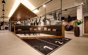 Moderne kantoorruimte aan de Frederiklaan 10E in Eindhoven Strijp-S met stijlvolle zitbank, hangende lampen en houten accenten. Ideaal voor wie kantoorruimte wil huren in een levendig kantoorpand.