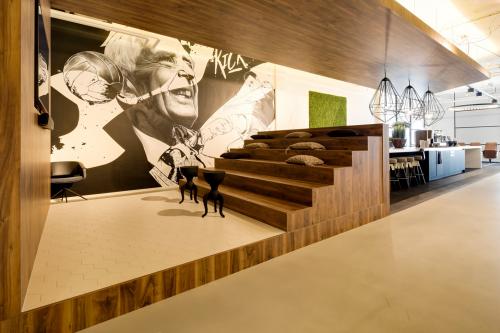 Modern ingerichte kantoorpand met houten trappen, kunst aan de muur en stijlvolle hanglampen op Frederiklaan 10E, Eindhoven Strijp-S. Ideaal voor bedrijfscultuur met ruimte voor creativiteit en bijeenkomst.