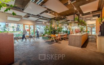 Ruime en moderne kantoorruimte met veel groen en grote ramen op Torenallee 20, Eindhoven Strijp-S. Ideaal voor kantoorruimte huren, ingericht met diverse werkplekken en een open indeling.