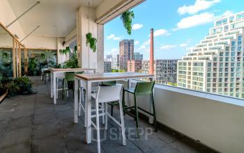 Buitenterras met moderne zitplaatsen en uitzicht op de skyline van Eindhoven Strijp-S, geschikt voor informeel werk of lunchpauzes.