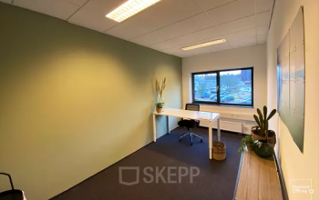 Interieur van het kantoorpand op Boermarkeweg 58a, Emmen, met een modern bureau, stoel en planten bij het raam. Ideale plek voor kantoorruimte huren.