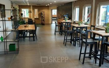 Kantoorpand op Hoenderkamp 20, Emmen met stijlvol ingerichte ruimte en hoge stoelen aan tafels langs de ramen. Ideaal voor wie kantoorruimte huren overweegt in Emmen.