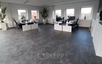 Ruime kantoorruimte huren in Hoenderkamp 20, Emmen met moderne inrichting, lichte wanden en grote ramen. Twee bureaus met stoelen en computers aanwezig, ideaal voor productief werken.