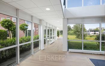 Ruimte met grote ramen en veel natuurlijk licht in het kantoorpand op Hoenderkamp 20, ideaal voor kantoorruimte huren in Emmen. De open omgeving biedt een frisse uitstraling met uitzicht op de buitenomgeving.