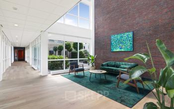 Moderne kantoorruimte huren aan Hoenderkamp 20 in Emmen, met een strakke inrichting. Verlaagde plafonds en grote ramen zorgen voor veel natuurlijk licht, terwijl planten en kunstwerken een stijlvolle touch geven.