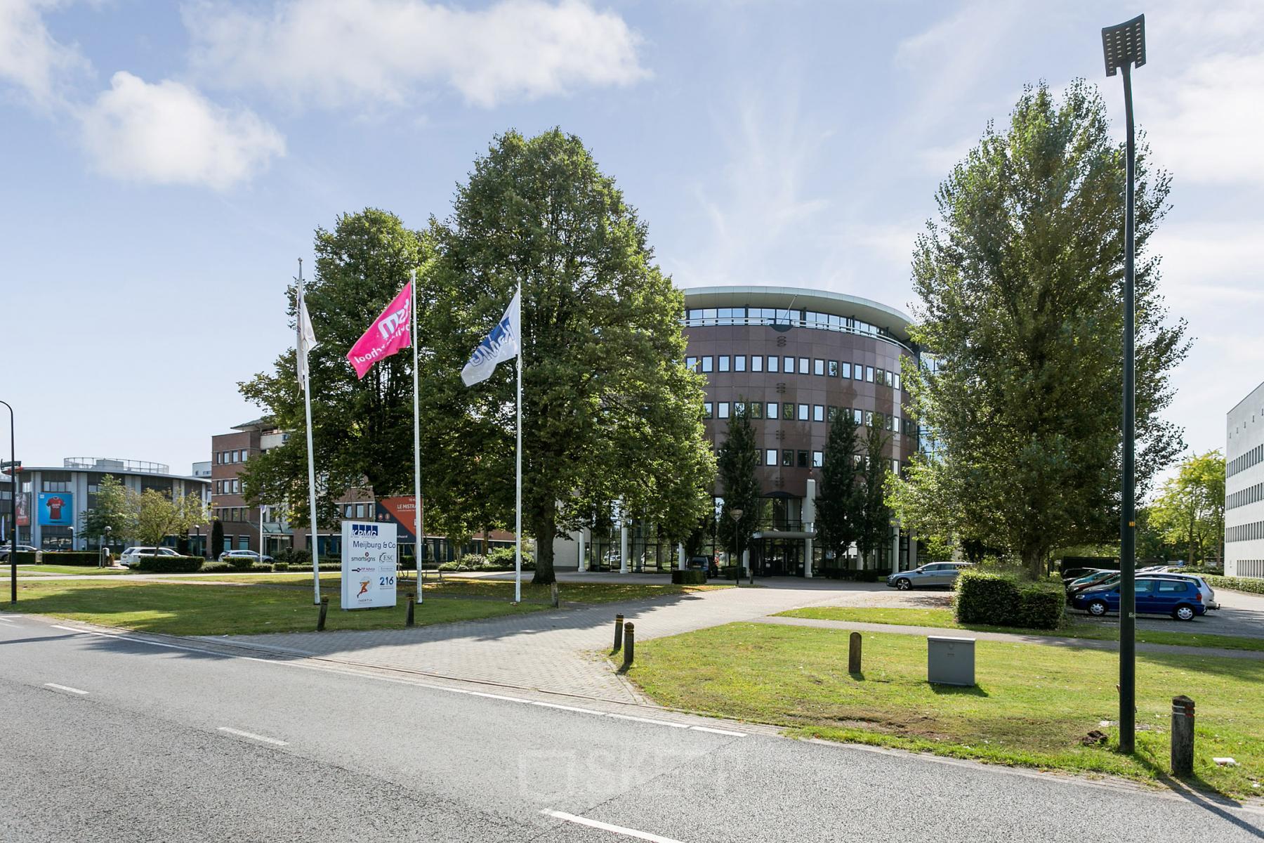 Kantoorpand met meerdere verdiepingen op Hengelosestraat 581, Enschede. Uitgestrekte groene buitenruimte met vlaggen en oprijlaan.