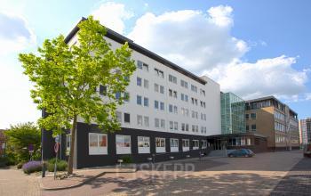 Exterieur van een modern kantoorpand op Brouwerijstraat 1, Enschede, met parkeerplekken en groen. Ideaal voor wie op zoek is naar kantoorruimte huren in een toegankelijke omgeving.