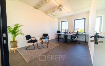 In het kantoorpand aan de Brouwerijstraat 1 in Enschede zie je een ruime werkplek met bureaus, stoelen en een vloerkleed. Kantoorruimte huren hier biedt een stijlvolle en functionele omgeving.