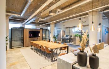 Modern ingericht kantoorpand aan Brouwerijstraat 1 in Enschede, met een grote vergadertafel en sfeervolle verlichting.