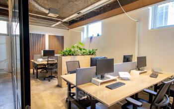 Moderne kantoorruimte op Brouwerijstraat 1 in Enschede met werkplekken voorzien van bureaus, stoelen en computeruitrusting. Natuurlijk licht valt binnen door ramen bovenin.