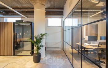 Moderne kantoorruimte huren in Enschede op Brouwerijstraat 1, met glazen wanden en enkele werkplekken.