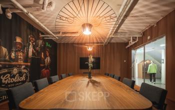 Vergaderruimte in kantoorpand op Brouwerijstraat 1, Enschede, met lange houten tafel, comfortabele stoelen en sfeervolle verlichting.