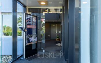 Ingang van kantoorpand op Marssteden 20 in Enschede met moderne glazen deuren en informatiezuil. Ideale plek voor kantoorruimte huren.
