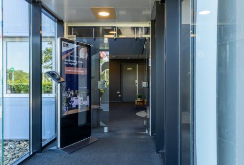 Ingang van kantoorpand op Marssteden 20 in Enschede met moderne glazen deuren en informatiezuil. Ideale plek voor kantoorruimte huren.