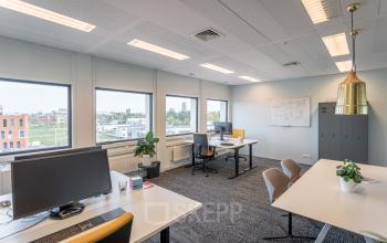 Kantoorruimte huren in Enschede op Wethouder Beversstraat 185 met uitzicht, bureaus en stoelen. Moderne verlichting en opslagkast aanwezig.