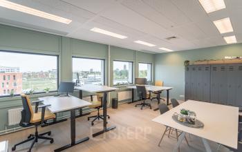 Lichte kantoorruimte met uitzicht op Enschede, ingericht met verstelbare bureaus, stoelen en kluisjes; ideaal voor comfortabel werken. Kantoorruimte huren biedt flexibiliteit en een productieve omgeving.